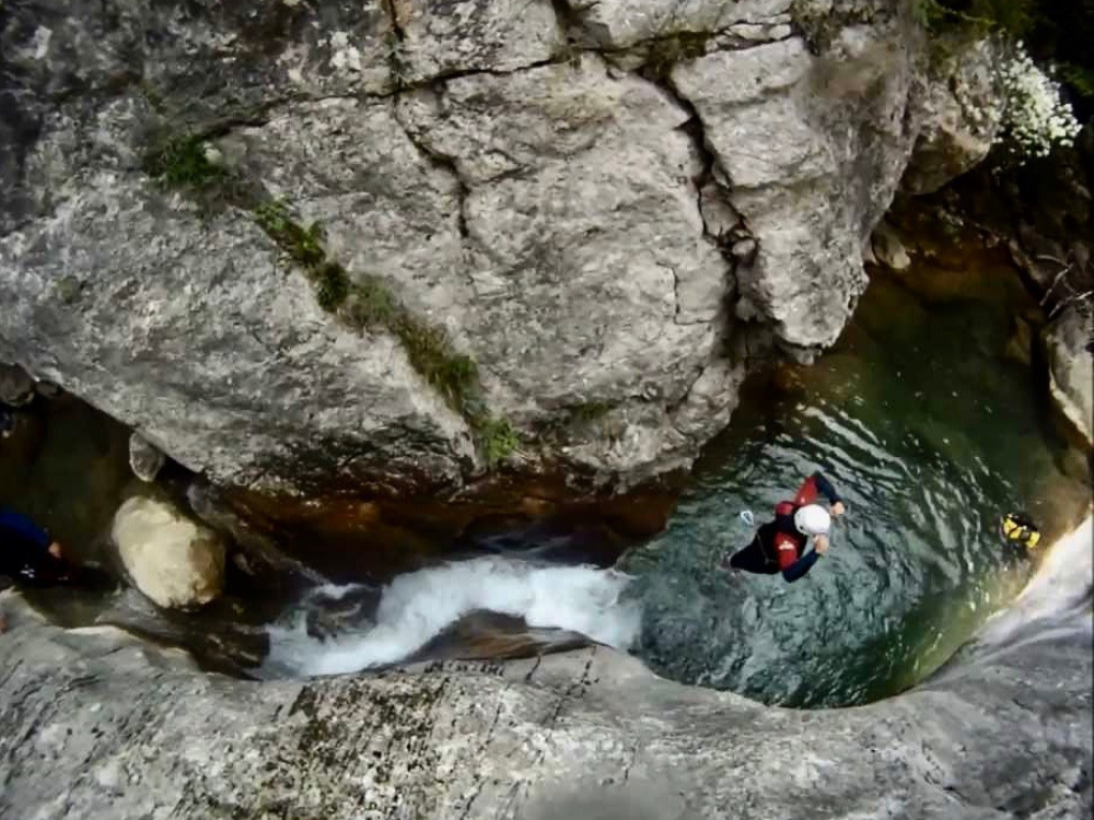 Barranc del Forat de Bóixols, salto de un excursionista equipado, en el forat. Rodeado este de grandes moles de piedra
