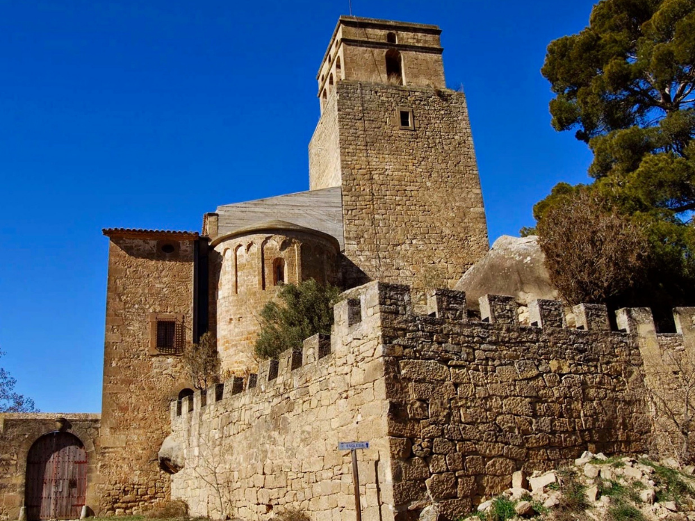 Castell de Ribelles, vista del castell amb les seves muralles, el fossat que l'envolta i al centre la torre d'homenatge sota un cel blau