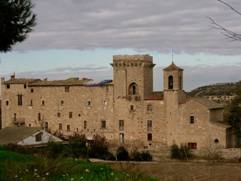 Castell de la Floresta, view of the castle with a small mountain in the background. On the right is the church, following the tower to the left and then the building on the right.