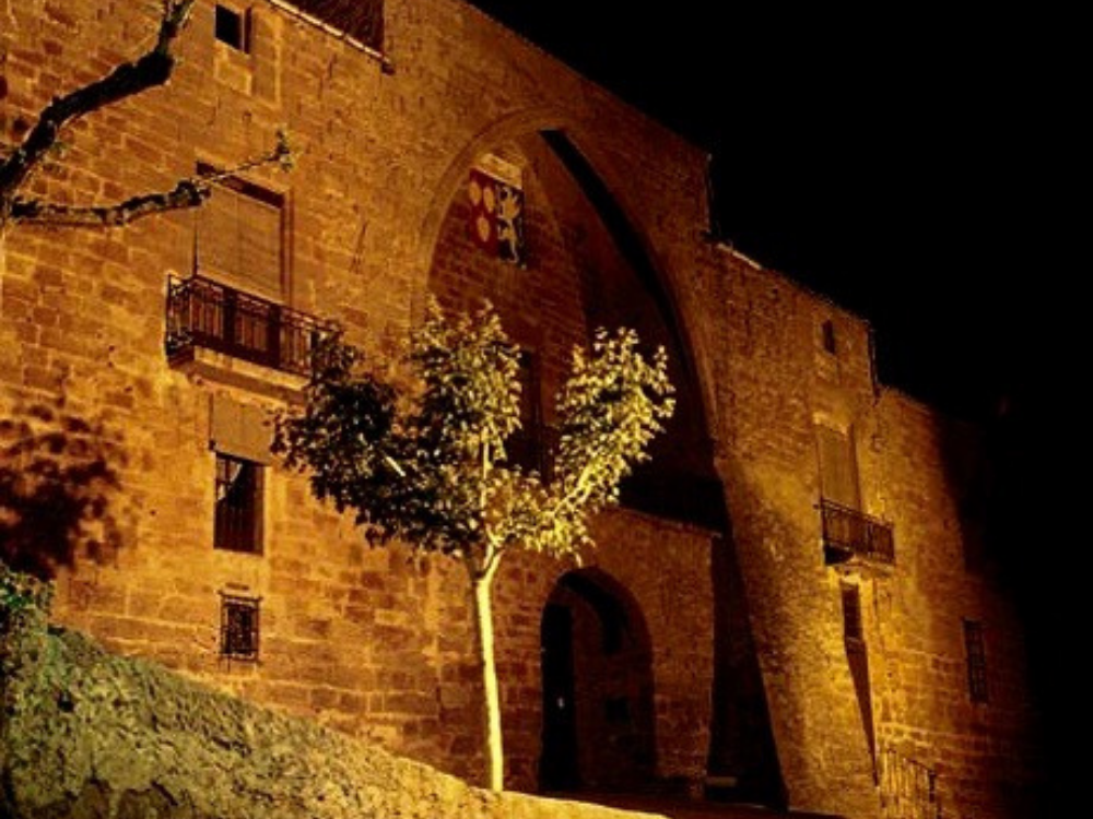 Castell de les Pallargues, fachada del castillo encima de la puerta principal una gran bóveda con el escudo en el centro. Iluminación nocturna en toda la fachada principal del castillo