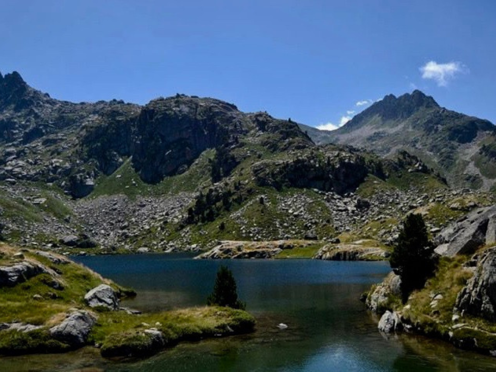 Llac major de Colomer, grans muntanyes que arriben al llac, amb un cel blau d´estiu