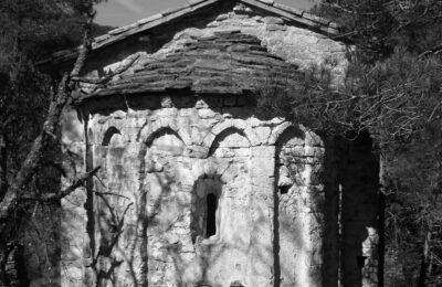 Imagen en blanco y negro de Sant Martí de Terrasola. Foto en blanco y negro apreciándose las nítidamente sombras de los árboles en el exterior del ábside de la ermita