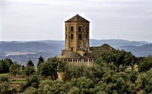 Vista de Sant Pere de Ponts, es pot veure la torre i dos dels seus tres absis, al fons es veuen muntanyes