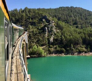 Vista del tren pasando por un puente cruzando un lago