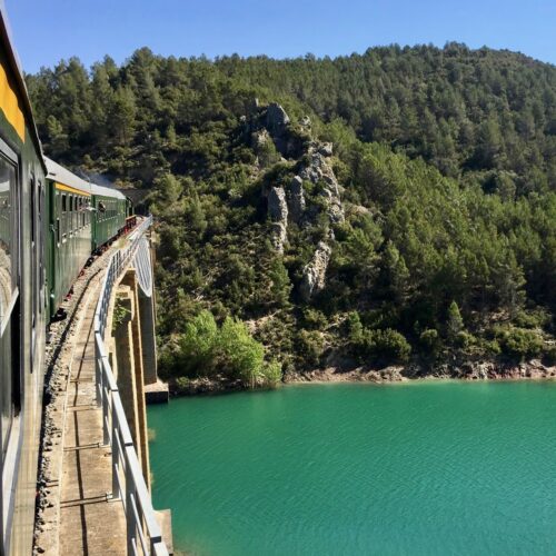Vista del tren pasando por un puente cruzando un lago