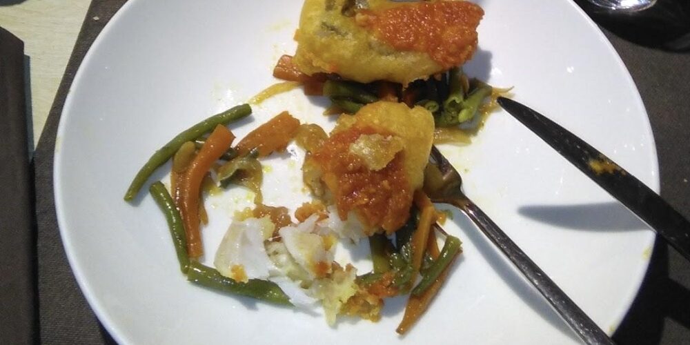 Plat cuinat de bacallà amb el seu acompanyament de verdures i salsa de tomàquet
